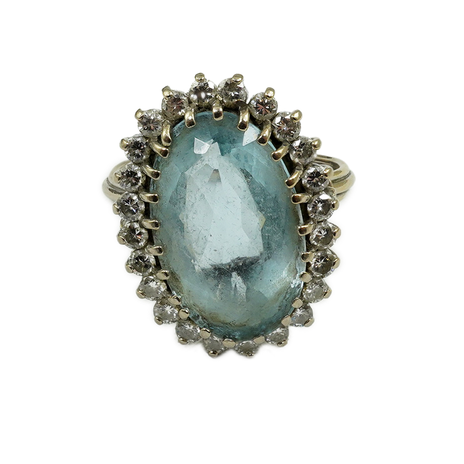 A white gold and single stone oval cut aquamarine set dress ring, with diamond cluster set border